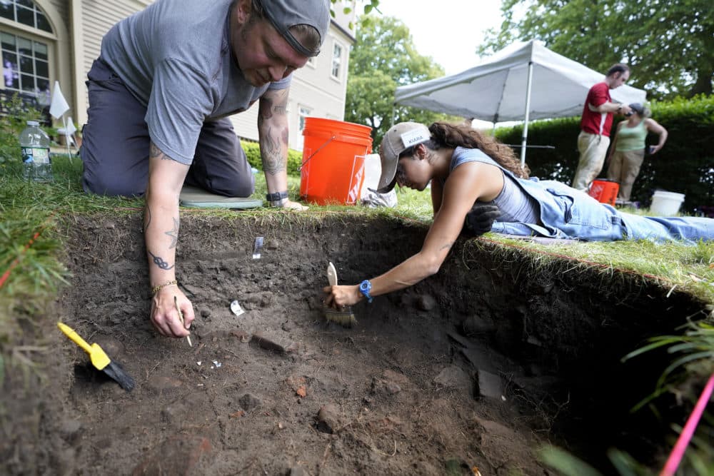 UMass Boston graduate students Nicholas Densley and Kiara Montes use brushes while searching for artifacts at the excavation site on Wednesday on Cole's Hill, in Plymouth. (Steven Senne/AP)