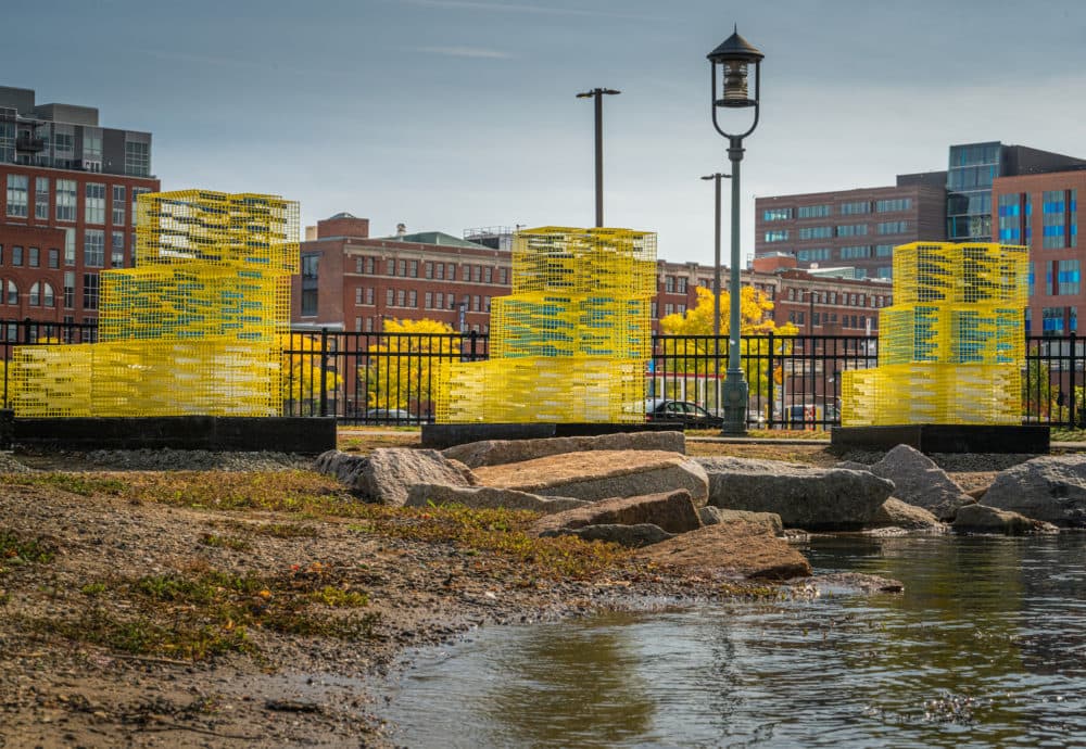 Yellow lobster cages on land model how a proposed berm could serve as a wall, blocking the flooding at three different heights. (Courtesy Matt Conti)