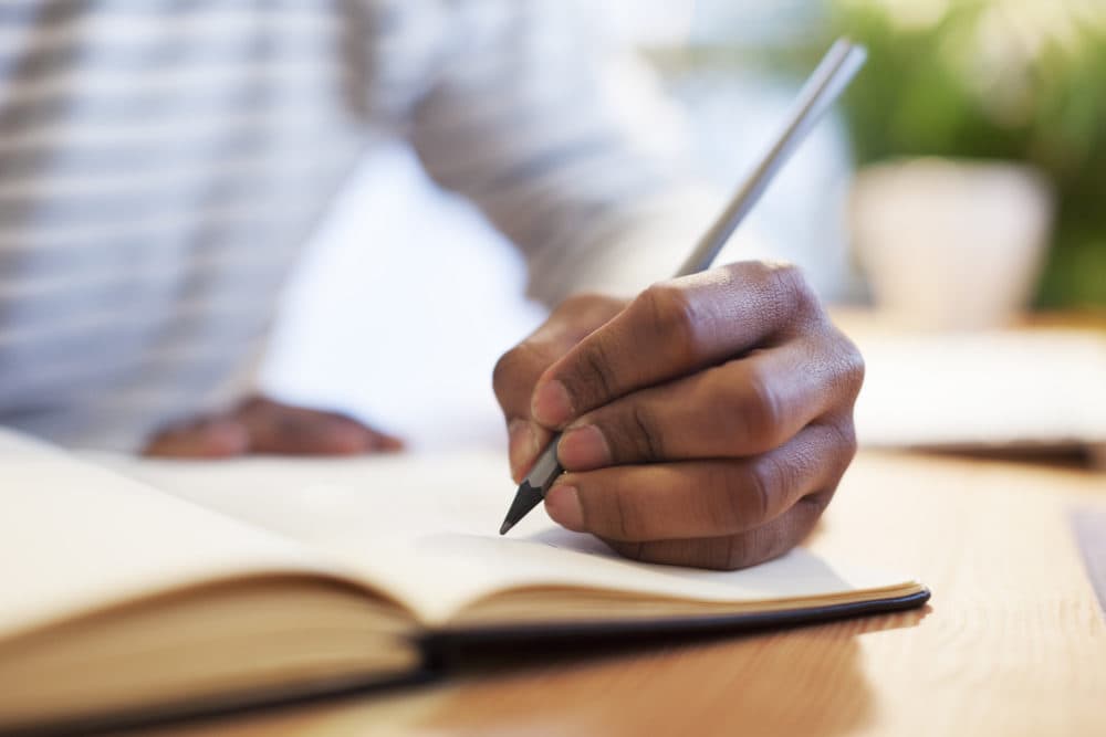 Man's hand drawing in a notebook (Getty Images)