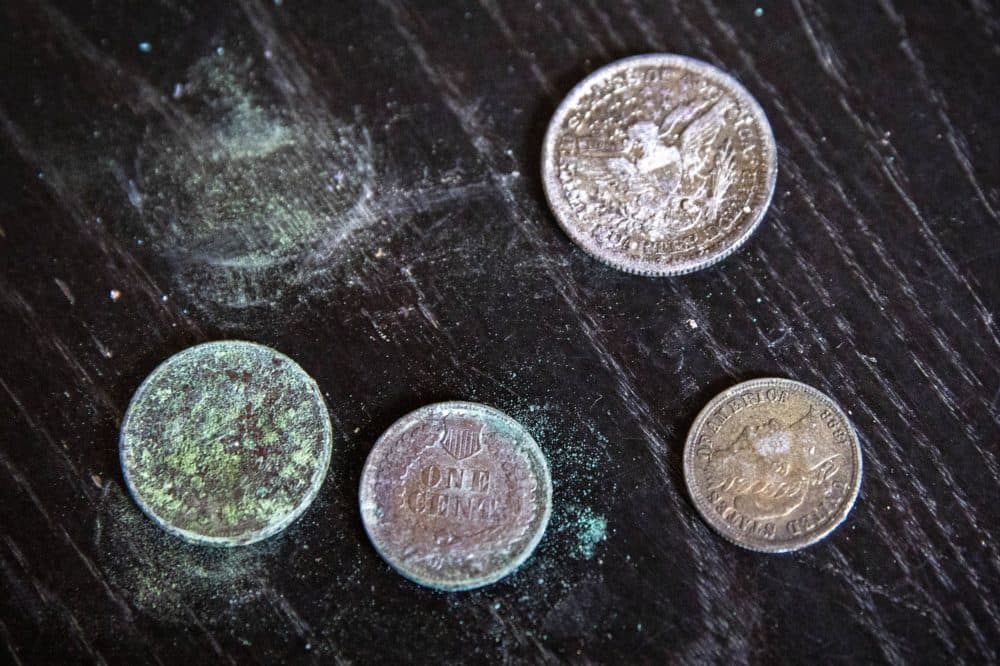 Four coins that were found inside a bundle of papers in the box. (Robin Lubbock/WBUR)