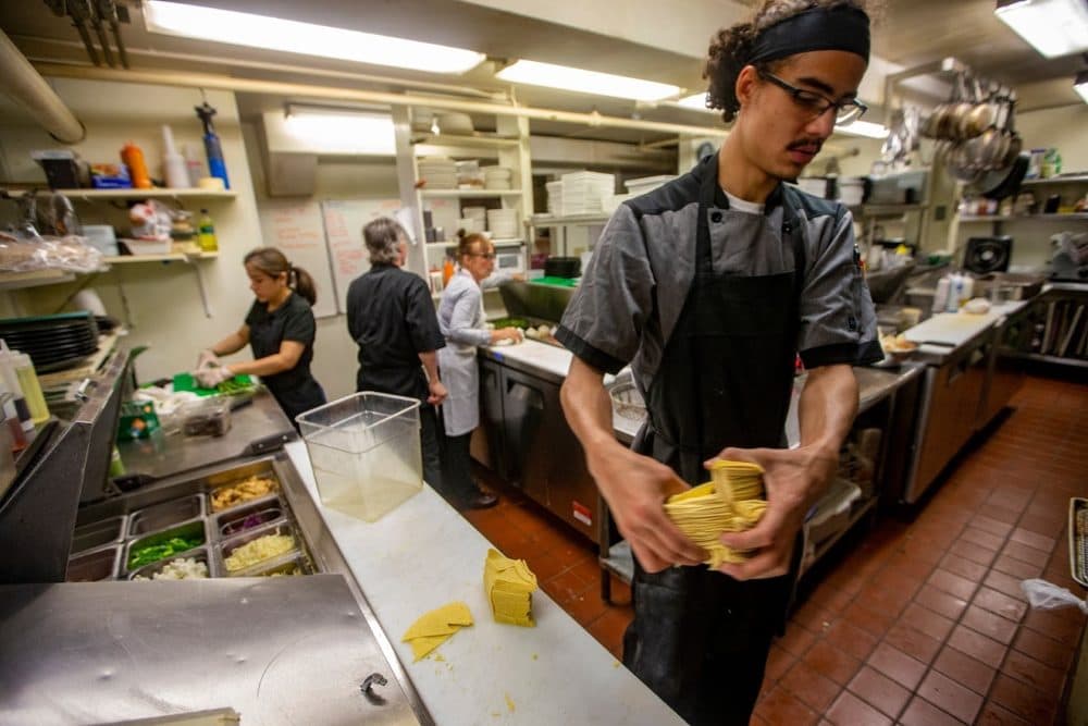 Brandon Ford lifts a pile of corn tortillas from the counter to place in a frialator to make chips in the very busy kitchen at the Waterhouse Restaurant in Peterborugh, NH. (Jesse Costa/WBUR)