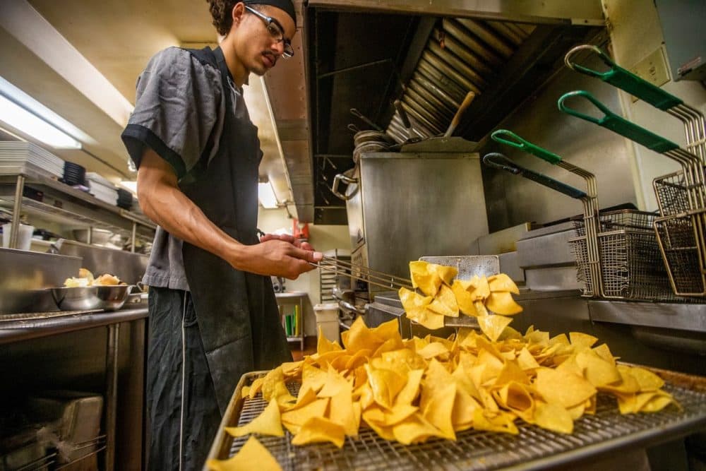 Brandon Ford removes tortilla chips from a frialator for the lunchtime crowd in the very busy kitchen at the Waterhouse Restaurant in Peterborugh, NH. (Jesse Costa/WBUR)