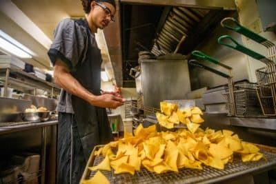 Brandon Ford removes tortilla chips from a frialator for the lunchtime crowd in the very busy kitchen at the Waterhouse Restaurant in Peterborough, NH. (Jesse Costa/WBUR)