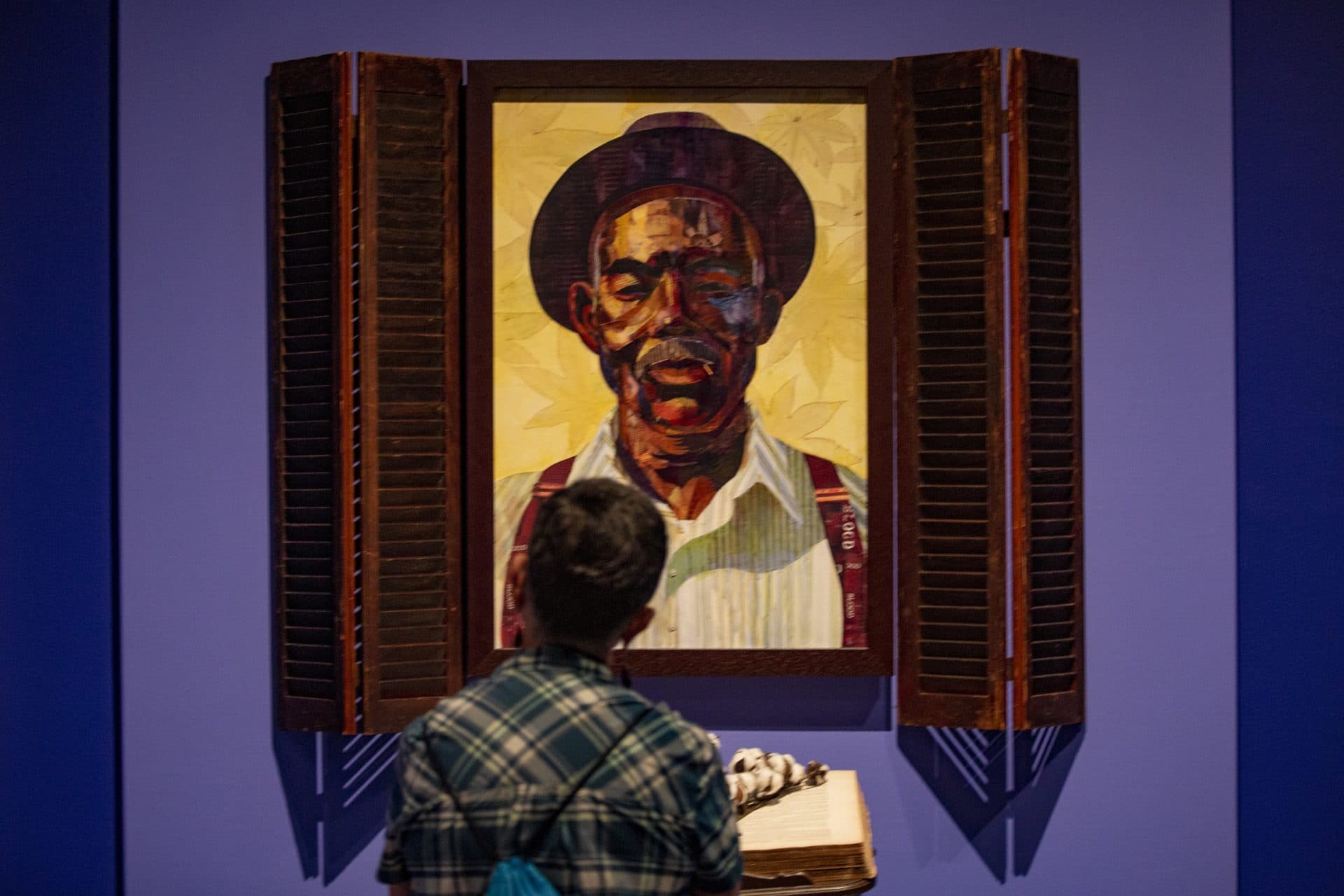 Emily Farmer examines “Idyll of the South: Root of Jesse,” a work which features Ekua Holmes’ grandfather. (Jesse Costa/WBUR)