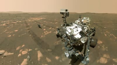 This April 6, 2021 image, made available by NASA, shows the Perseverance Mars rover, the foreground, and the Ingenuity helicopter about 13 feet behind.  This composite image was made by the WASTON camera on the rover's robotic arm on the 46th of March, or Sun, of the mission.  (NASA / JPL-Caltech / MSSS via AP)