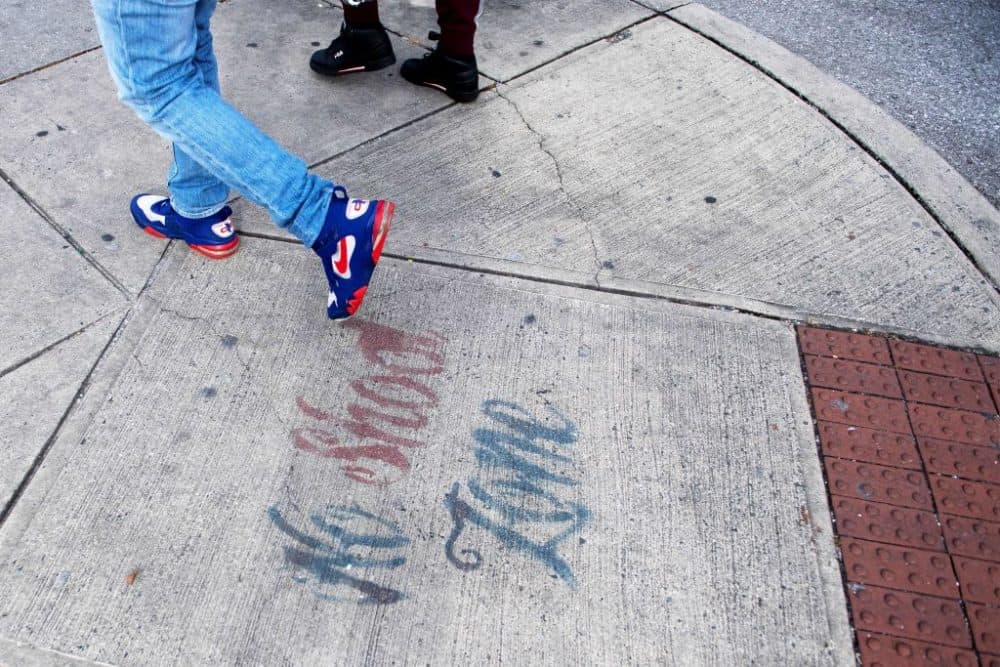 Two men walk past a sign spray painted on the sidewalk stating "No Shoot Zone" in Baltimore, Maryland, on Dec. 17, 2018. (Jim Watson/AFP/Getty Images)