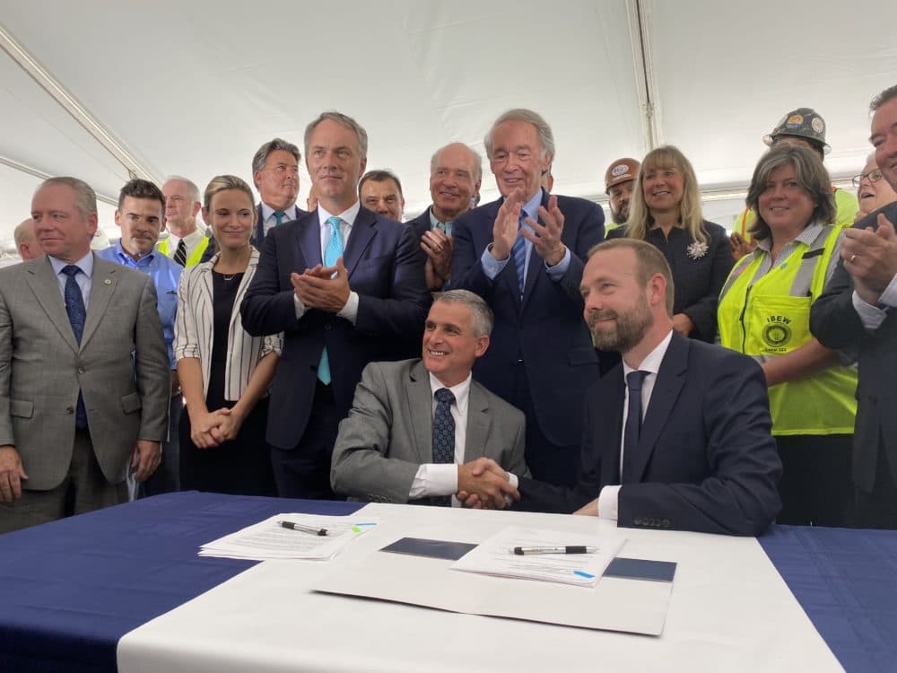 Southeastern Mass. Building Trades Council President David Araujo (left, seated) shakes hands with Vineyard Wind CEO Lars Pedersen after signing a project labor agreement at the New Bedford Marine Commerce Terminal. Miriam Wasser, WBUR