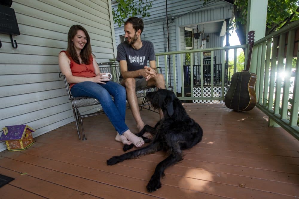 Ian Coss and his wife Kelsey and their dog hanging out on the front porch of their home. (Jesse Costa/WBUR)