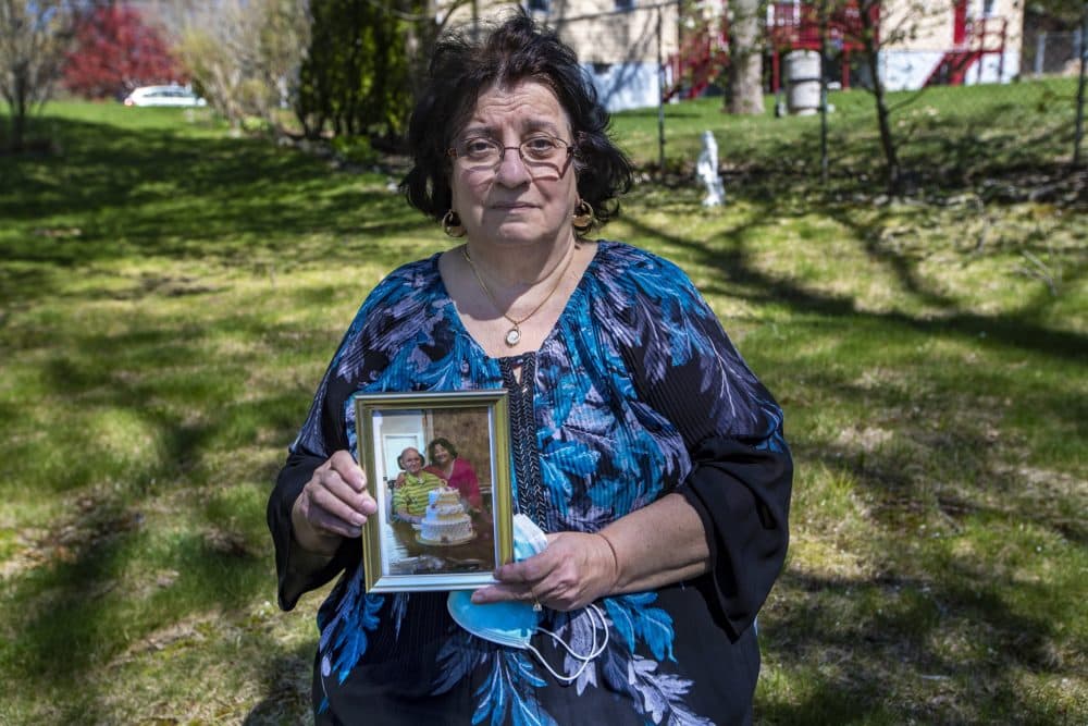Stella Kazantzas holding a photograph of  herself and her husband Nick in 2019, celebrating their 50th anniversary. (Jesse Costa/WBUR)