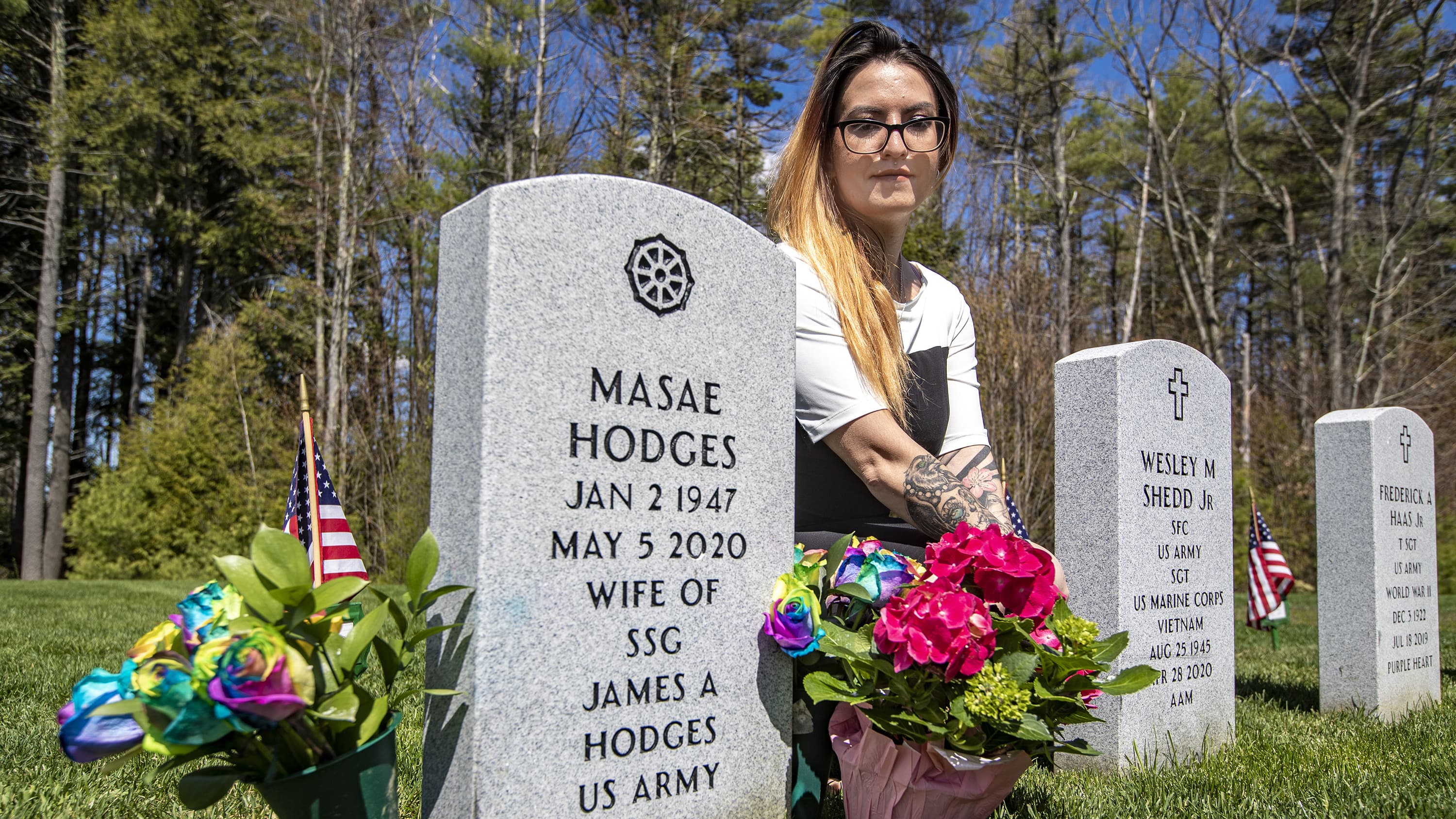 Suzanna Smith kneeling at the gravestone of her mother, Masae Hodges, at the Massachusetts Veterans’ Memorial Cemetery in Winchendon. (Jesse Costa/WBUR)