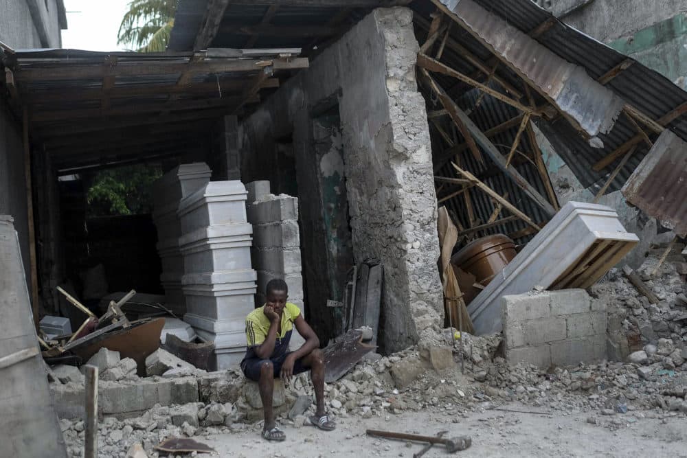 A man sits in front of a collapsed funeral home in Les Cayes, Haiti, Monday, Aug. 16, 2021, two days after a 7.2-magnitude earthquake struck the southwestern part of the country. (Matias Delacroix/AP)
