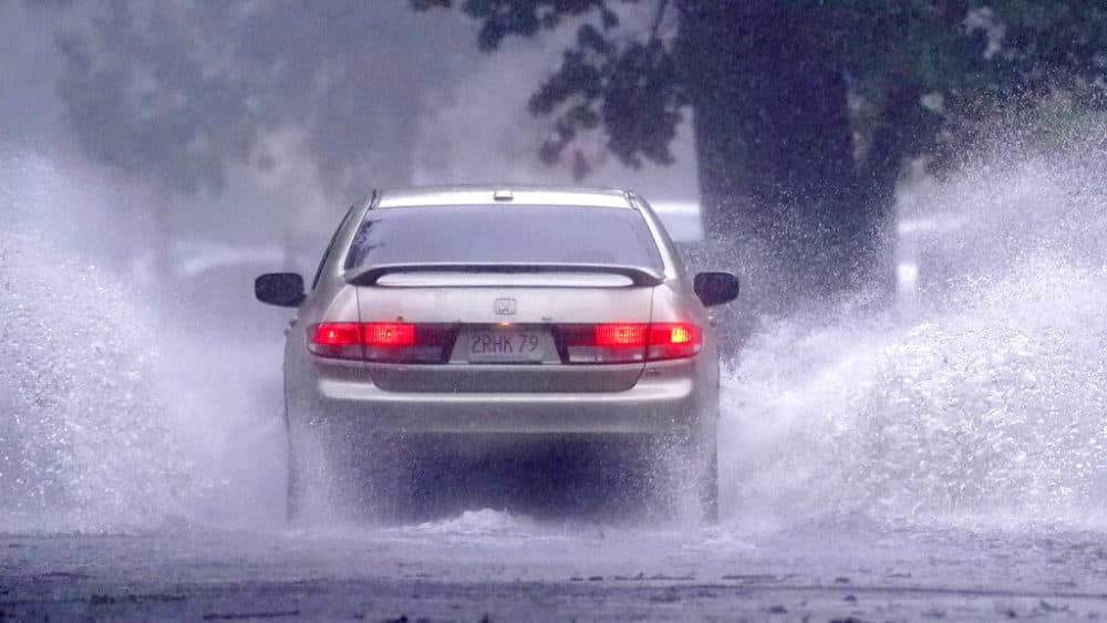 A car drives down a partially flooded street after the remnants of Tropical Storm Henri made landfall on Sunday in Springfield, Massachusetts. (Charles Krupa/AP)