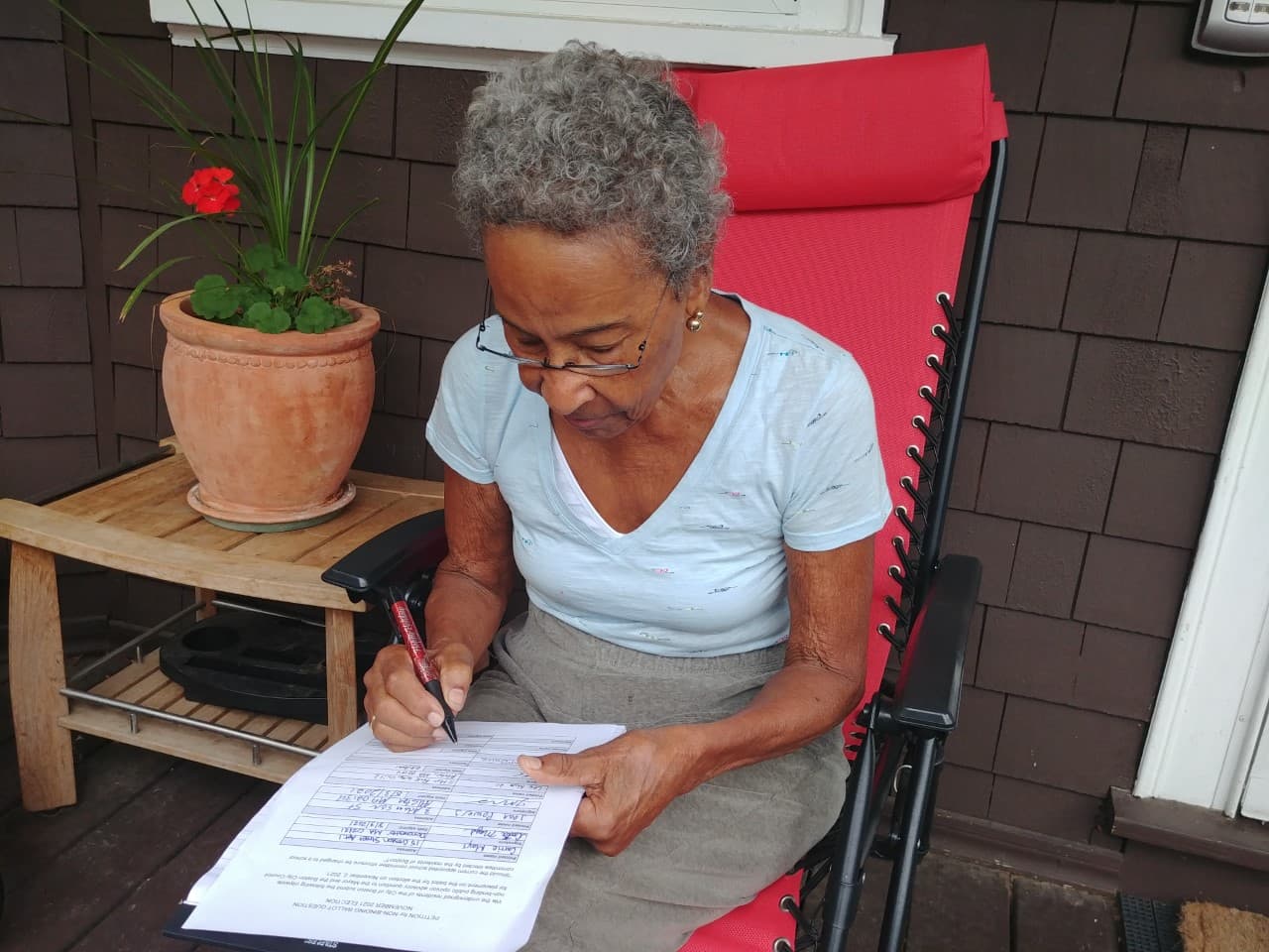 Jean McGuire signing the petition in support of restoring elections for the Boston School Committee. (Courtesy Alain Jehlen/Boston Coalition for Education Equity)