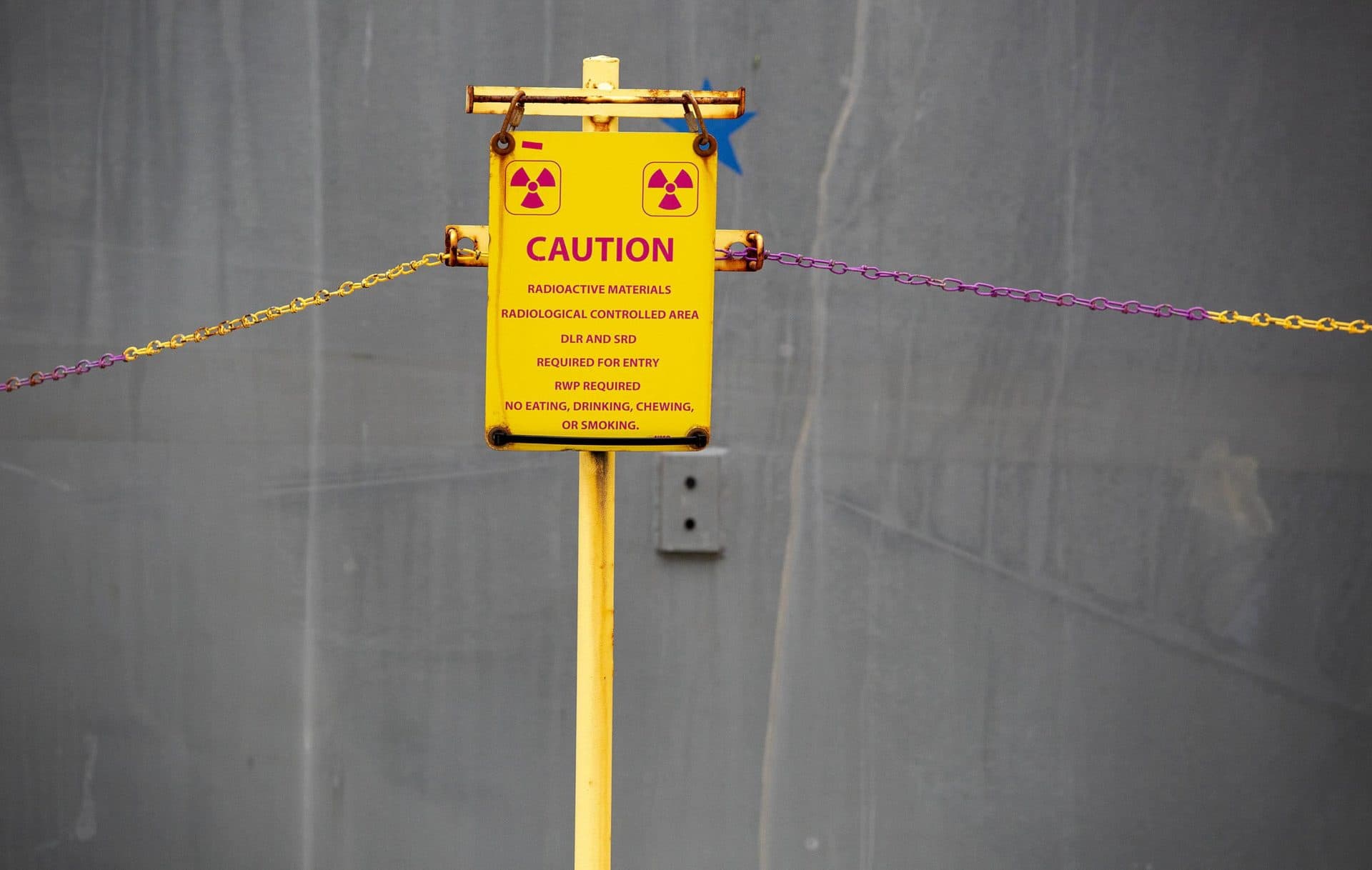 A sign by casks containing spent fuel on a concrete pad warns of the presence of radioactive materials. (Robin Lubbock/WBUR)