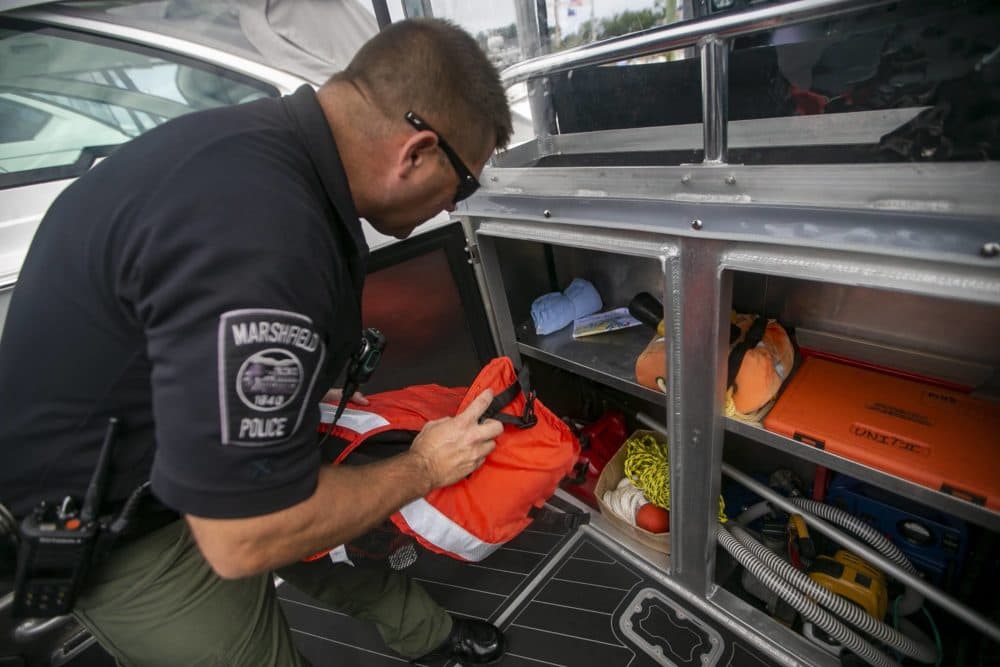 Marshfield Harbormaster Michael DiMeo pulls out a life vest before heading out on patrol. (Jesse Costa/WBUR)