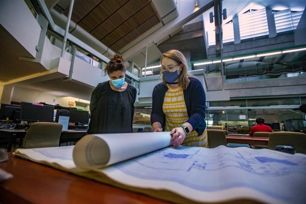 Caitlin Jones, head of Reference Services at the state archive, shows Laura Zigman the blueprints of the Fernald School in Waltham. (Jesse Costa/WBUR)