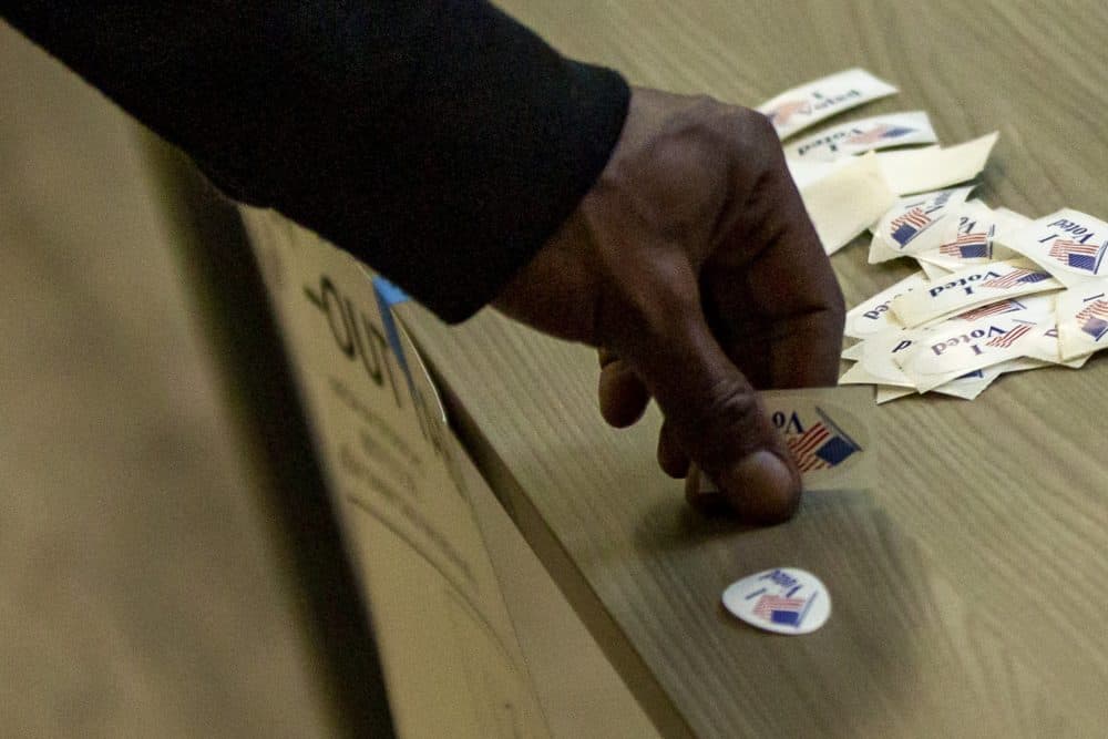 A Boston voter picks up an "I voted" sticker after voting in the preliminary election at a polling station in Dorchester's Upham's Corner. (Jesse Costa/WBUR)