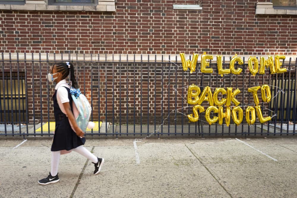 A girl passes a "Welcome Back to School" sign as she arrives for the first day of class an elementary school in New York on Sept. 13, 2021. (Mark Lennihan/AP/File)