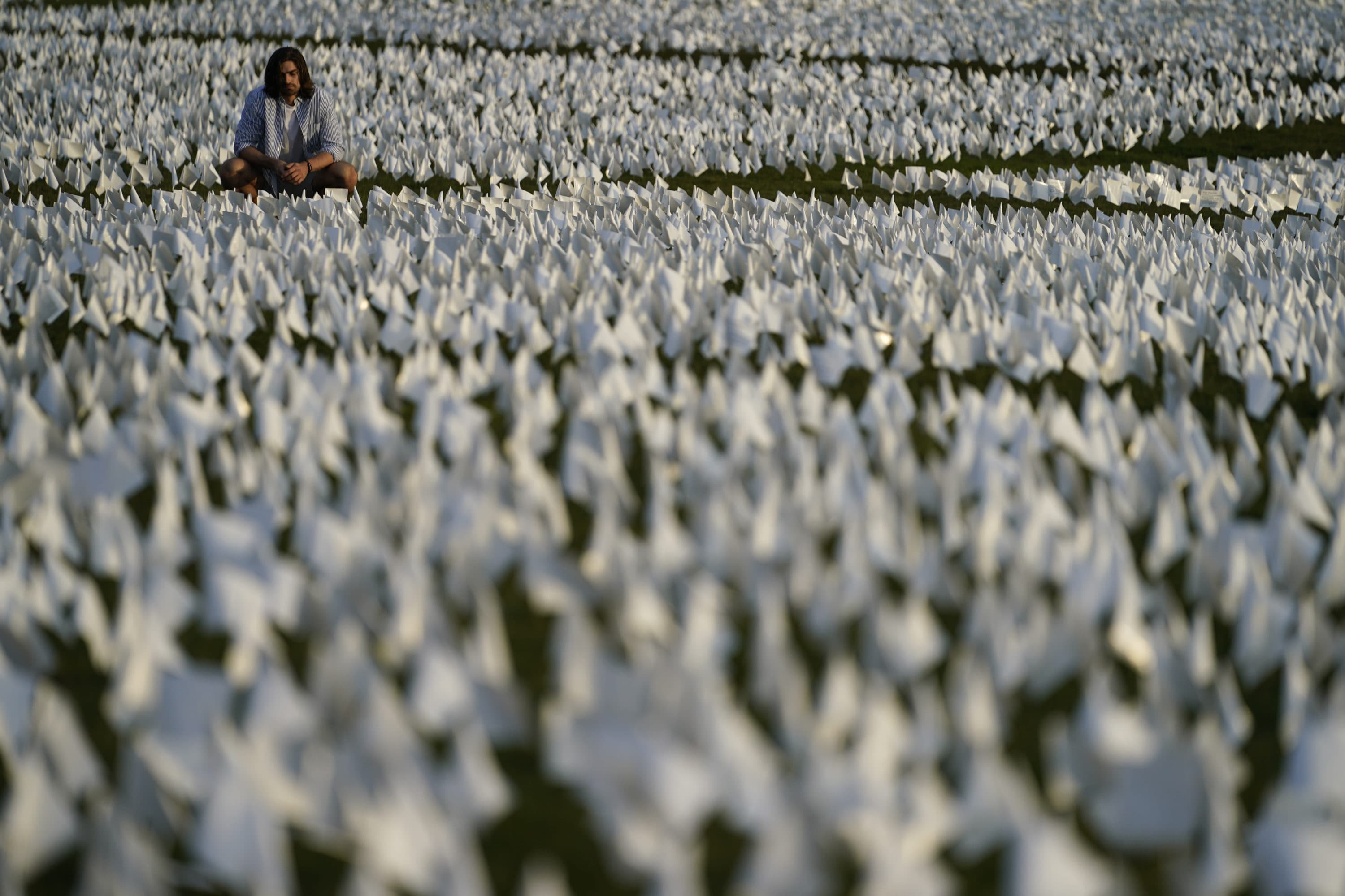 A person looks at white flags that are part of artist Suzanne Brennan Firstenberg's temporary art installation, "In America: Remember," in remembrance of Americans who have died of COVID-19, on the National Mall in Washington on Sept. 17, 2021. (Brynn Anderson/AP)