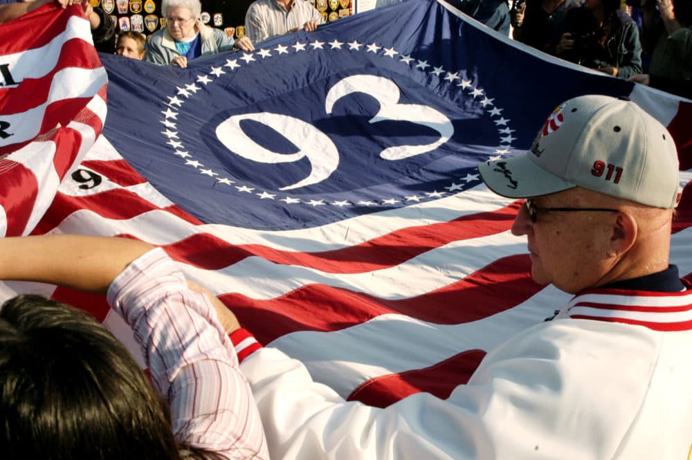 Visitors assist in unfolding a giant flag at a temporary memorial overlooking the crash site in Shanksville, Pennsylvania. The plane crashed Sept. 11, 2001, into a rural field from the presumed target of the nation's capital, killing 40 people. (Archie Carpenter/Getty Images)