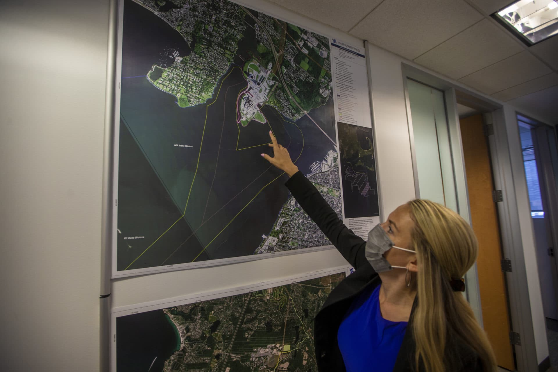 On a satellite image in the Mayflower Wind offices in Boston, Danielle Jensen points to an area where the power lines from the wind farm will come ashore at Brayton Point in Somerset. (Jesse Costa/WBUR)