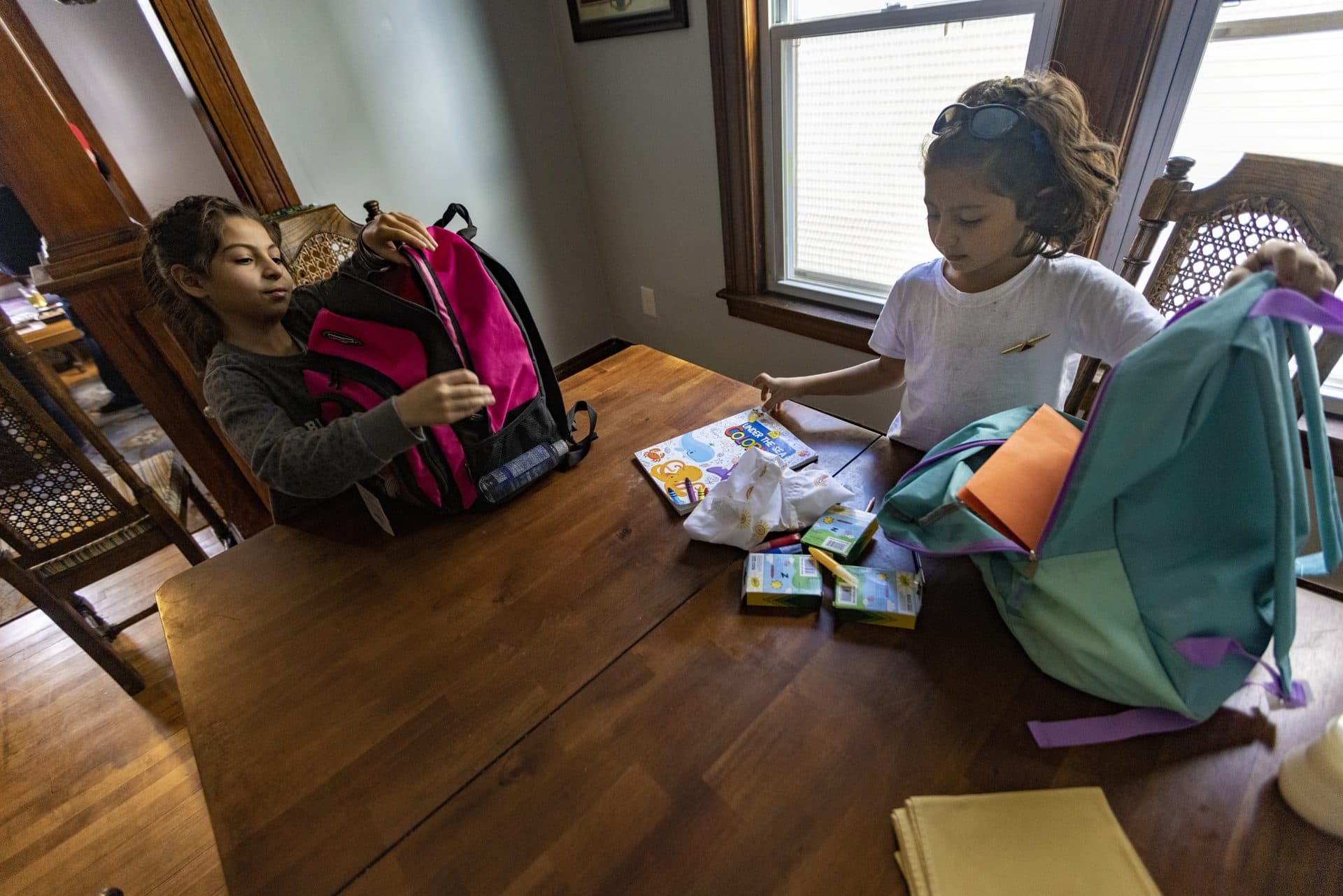 Khadija and Zahra Atayi open the backpacks that were donated to them. (Jesse Costa/WBUR)
