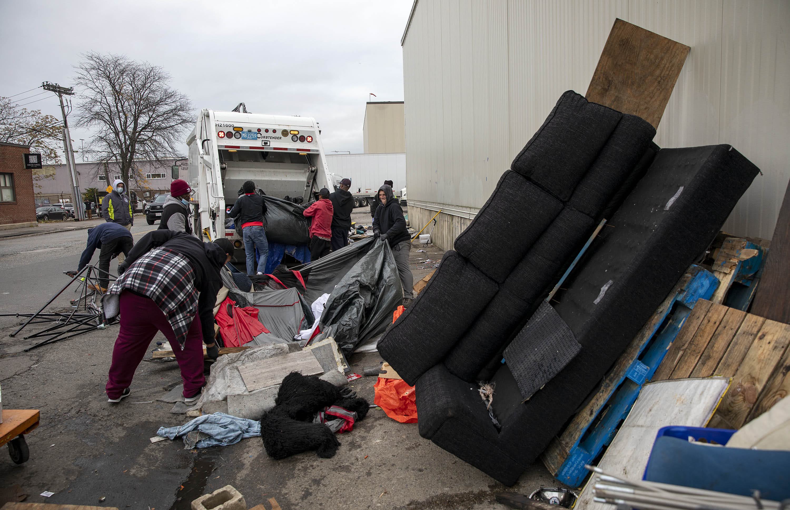 A Boston Public Health Commission crew throws material and furniture from makeshift shelters on Southampton Street into a garbage truck. (Robin Lubbock/WBUR)