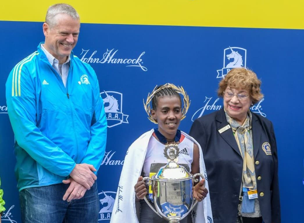 Gloria Ratti (right) with Boston Marathon winner Worknesh Degefa and Governor Charlie Baker at the finish line in 2019 (Courtesy of the Boston Athletic Association)