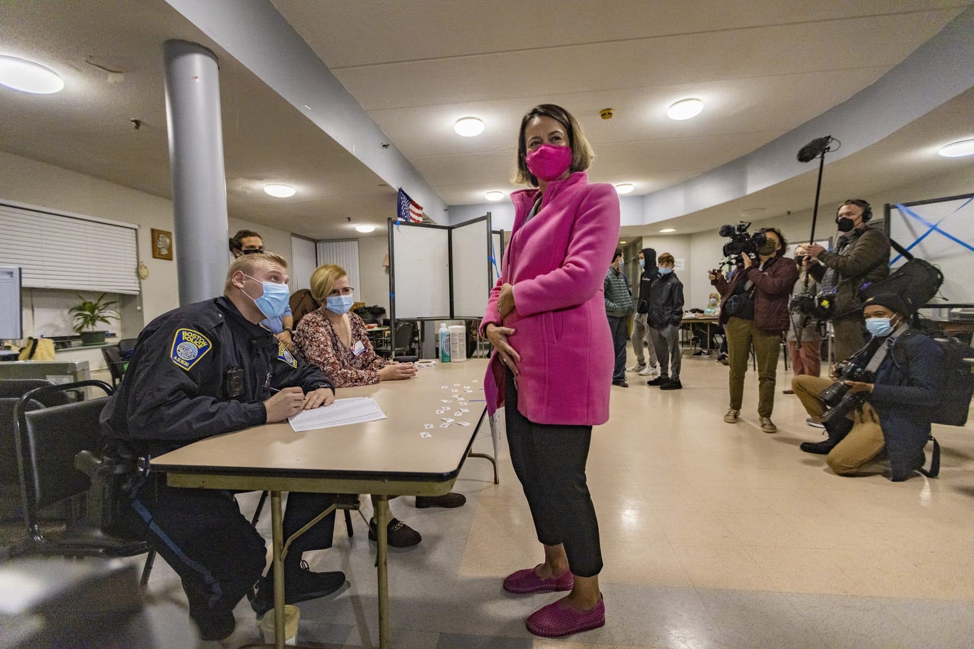 Annissa Essaibi George looks at the press and hides her ballot underneath her coat to keep prying eyes from seeing it before approaching the ballot box at the Bellflower Apartments in Dorchester. (Jesse Costa/WBUR)