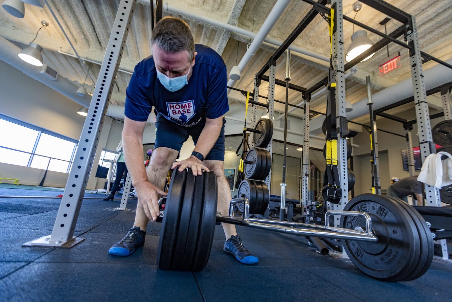 James Knauer adds more weigh to the weight bar in the gym at Home Base in Charlestown. (Jesse Costa/WBUR)