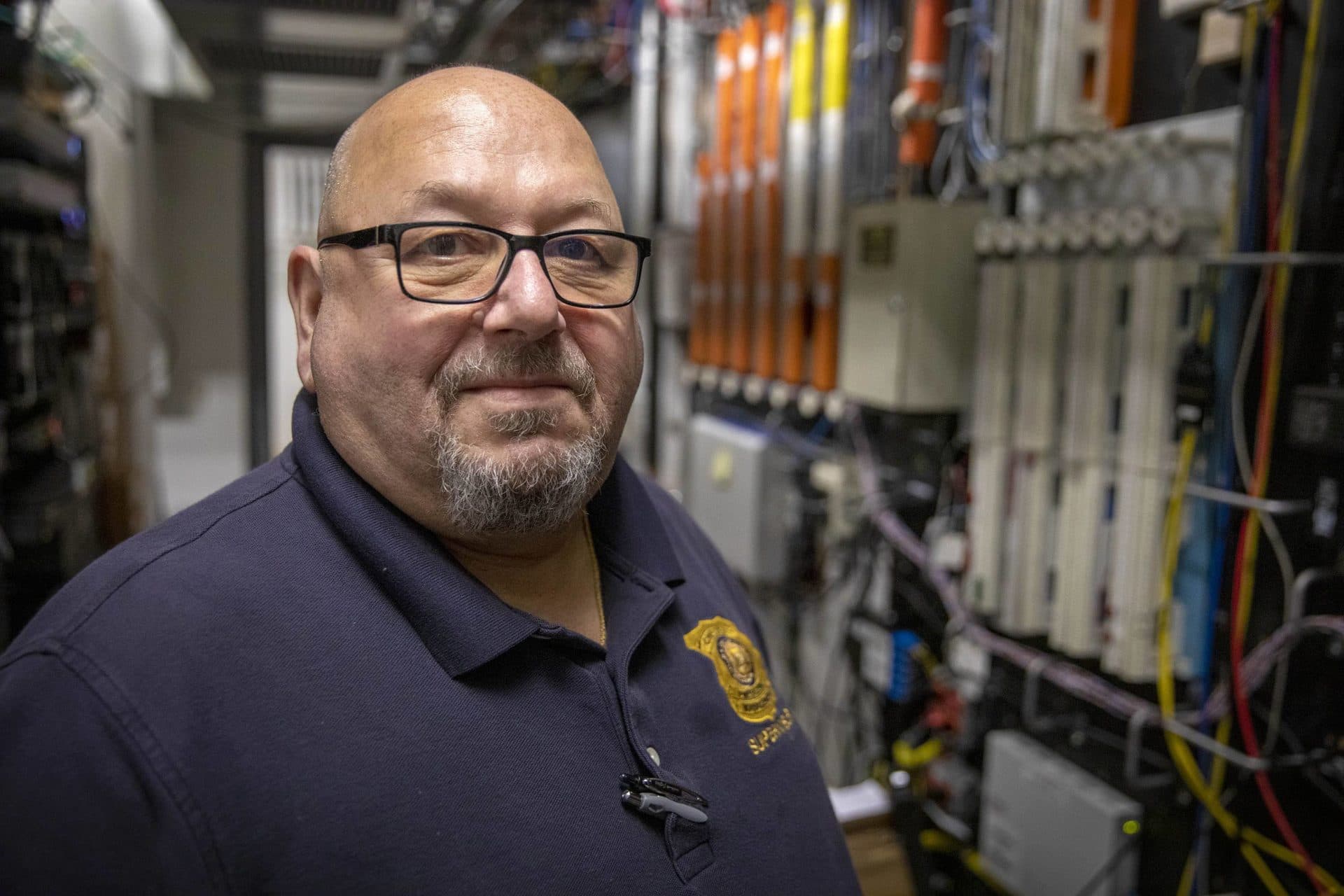 Paul Kooloian, Chelsea's 911 dispatch supervisor, surrounded by electronic equipment in the basement of the dispatch center. (Robin Lubbock/WBUR)