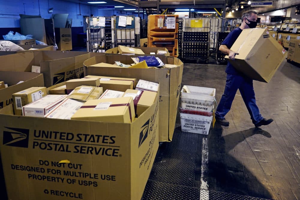 A worker carries a large parcel at the United States Postal Service sorting and processing facility, Thursday, Nov. 18, 2021, in Boston. (Charles Krupa/AP)