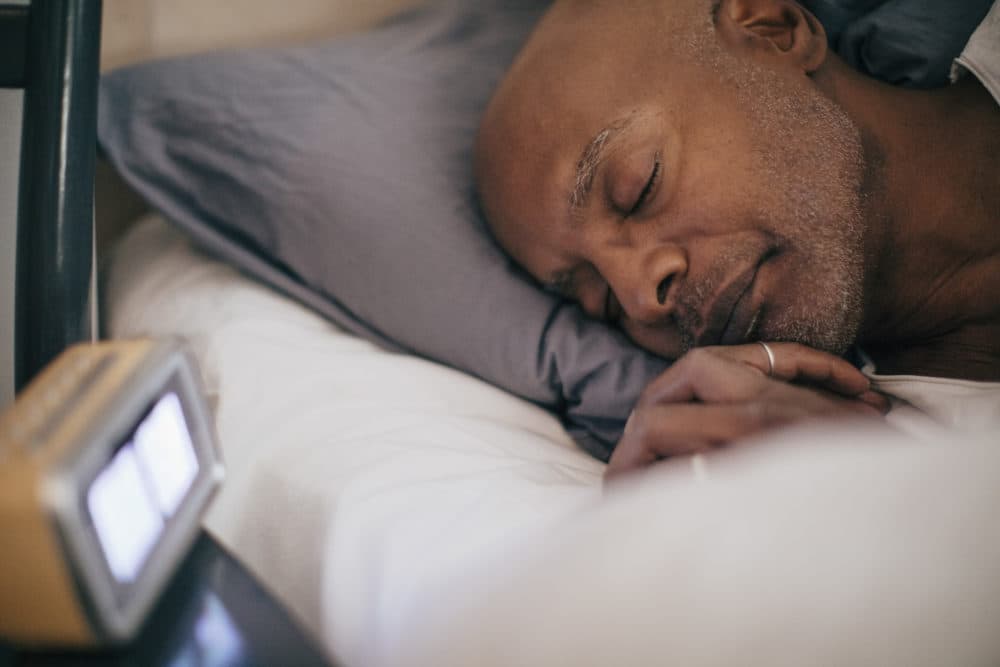 Retired senior man sleeping on bed by alarm clock at home (Getty Images)