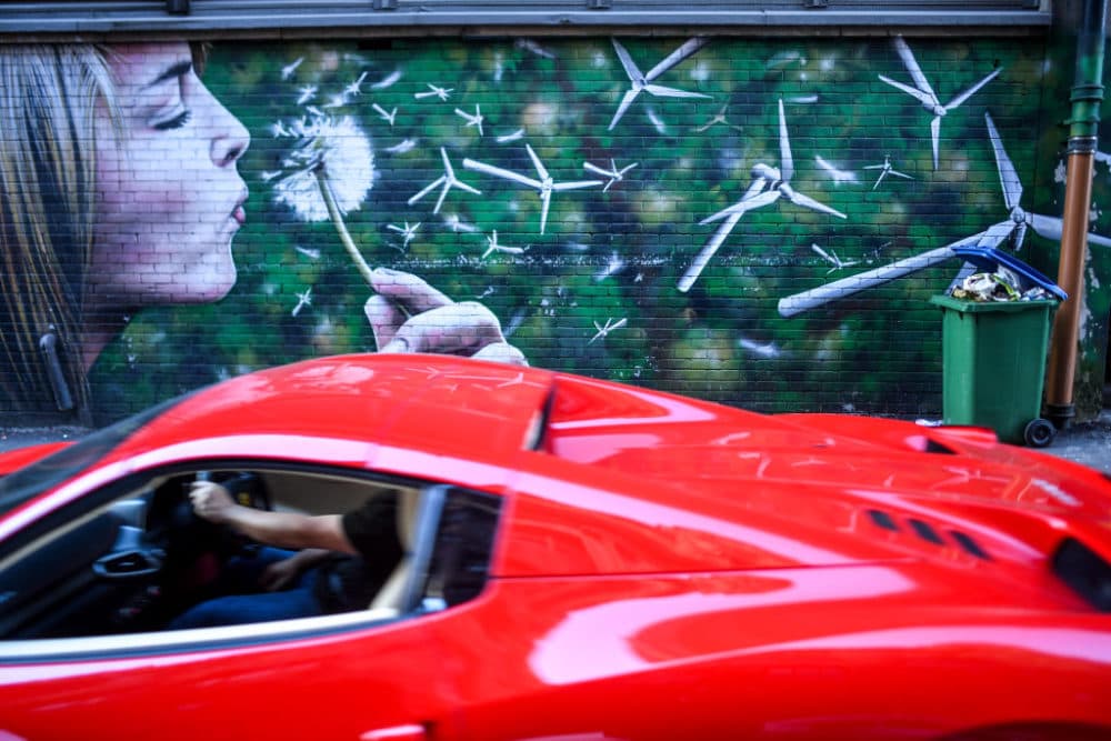 A Ferrari drives past a mural depicting Dandelion buds as wind turbines and an overflowing bin on November 3, 2021 in Glasgow, United Kingdom. As World Leaders meet to discuss climate change at the COP26 Summit, many climate action groups have taken to the streets to protest for real progress to be made by governments to reduce carbon emissions, clean up the oceans, reduce fossil fuel use and other issues relating to global heating. (Peter Summers/Getty Images)