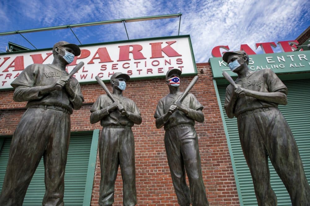 The statues of Ted Williams, Bobby Doerr, Johnny Pesky and Dom DiMaggio wear masks outside of Fenway Park. (Jesse Costa/WBUR)