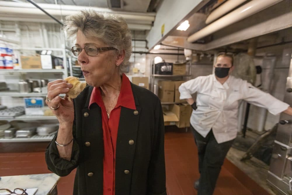 The hotel's historian, Susan Wilson, samples one of the Parker House rolls just out of the oven as baker Sheri Weisenberger watches for her assessment. (Jesse Costa/WBUR)