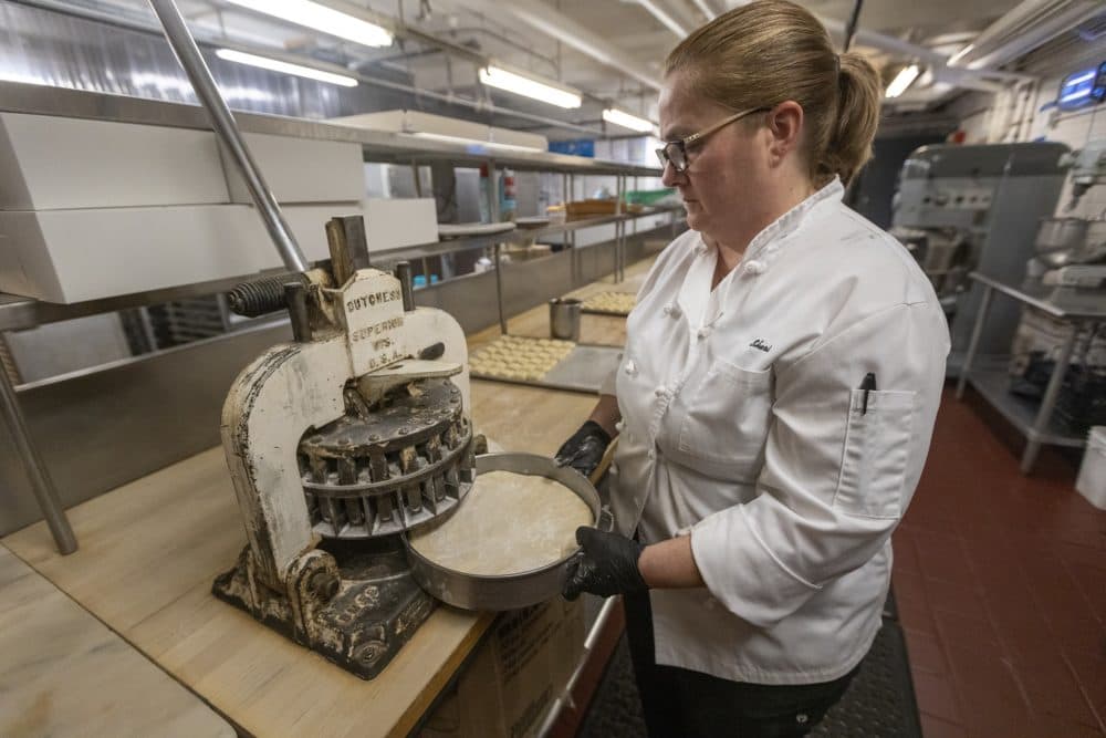 Omni Parker House baker Sheri Weisenberger places a pan of dough for Parker House rolls into a vintage dough cutter. Only three of their kind exist in the country. (Jesse Costa/WBUR)