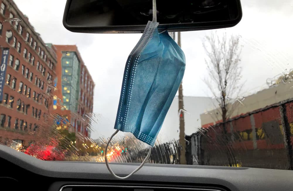 A mask hangs around a rear view mirror in a car in South Boston on November 12, 2021. (John Tlumacki/The Boston Globe via Getty Images)