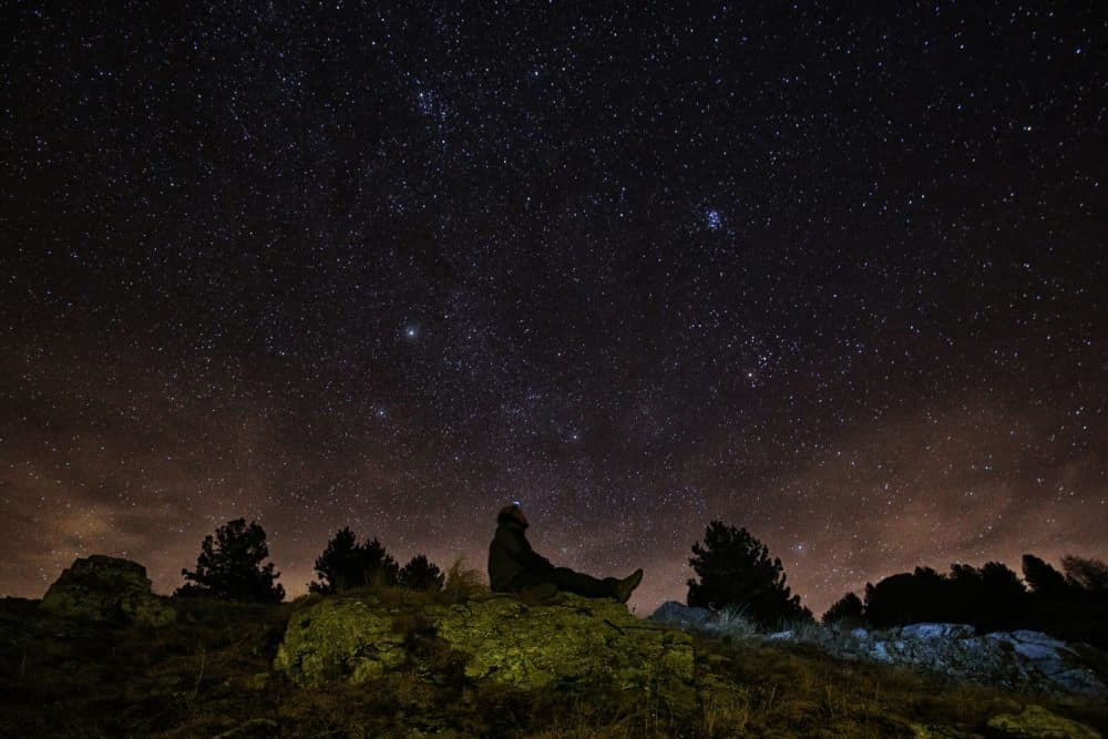 A photographer looks at the sky at night to see the annual Geminid meteor shower on the Elva Hill, in Maira Valley, near Cuneo, northern Italy on Dec. 12, 2015. (Marco Bertorello/AFP via Getty Images)