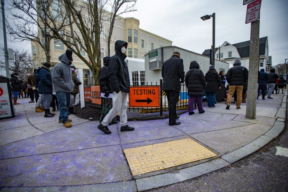 A long line of people inches slowly around the corner at the Bowdoin Street Health Center, many waiting over three hours, to receive a COVID-19 test. (Jesse Costa/WBUR)