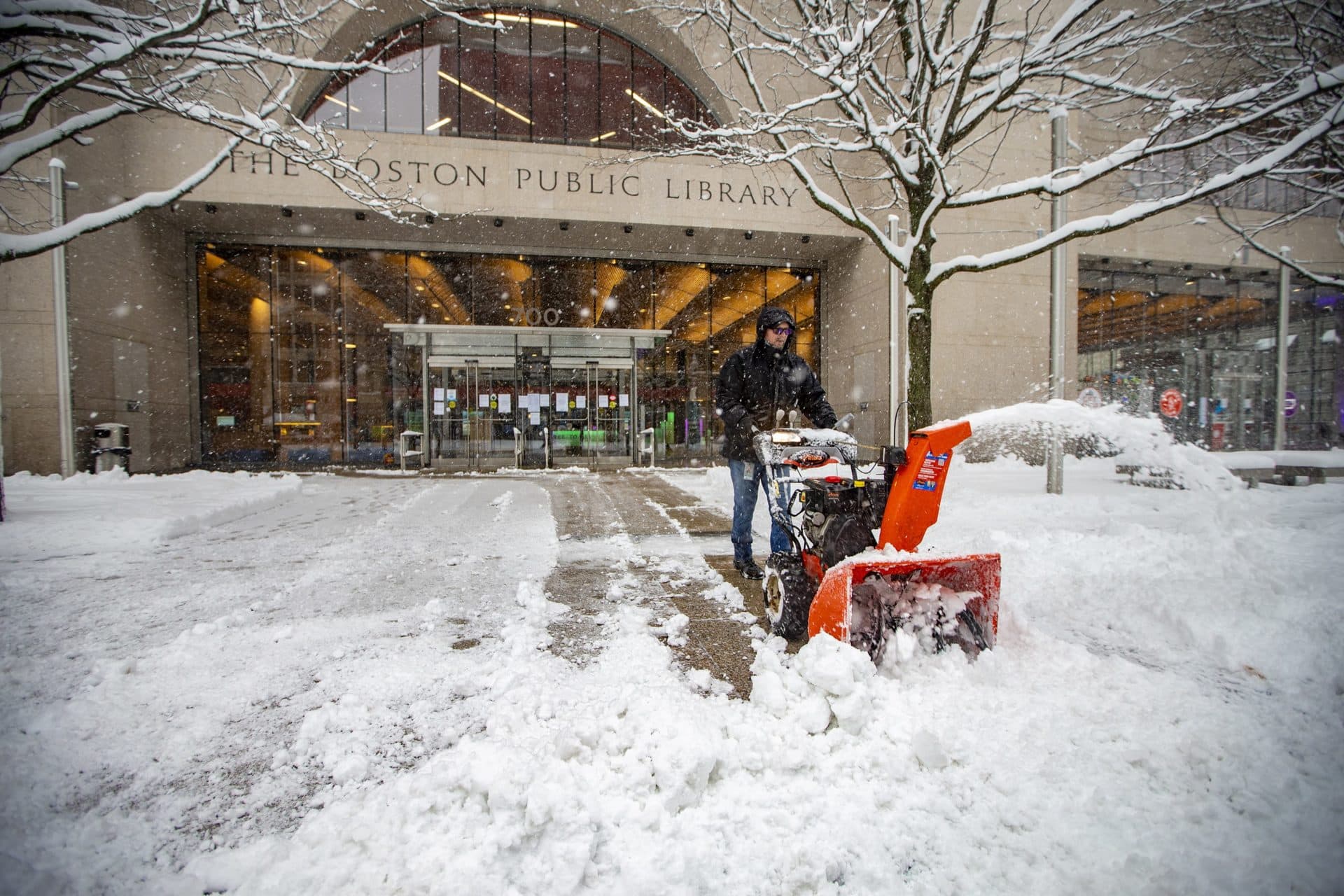 1st Snowstorm Closes Schools And Slows Travel, With Up To 10 Inches Possible Around Boston 4 A worker uses a snow blow to clear snow in front of the Boston Public Library on Friday morning. (Jesse Costa/WBUR)