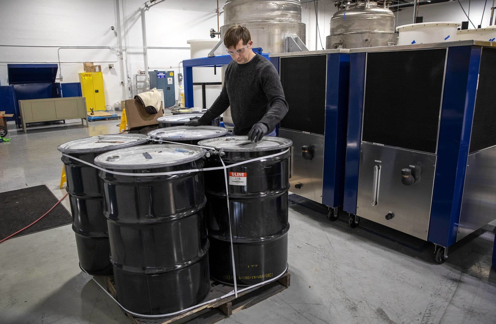 Eric Gratz, co-founder of Ascend Elements, examines barrels of "black mass" powder, made from shredded lithium batteries. (Robin Lubbock/WBUR)