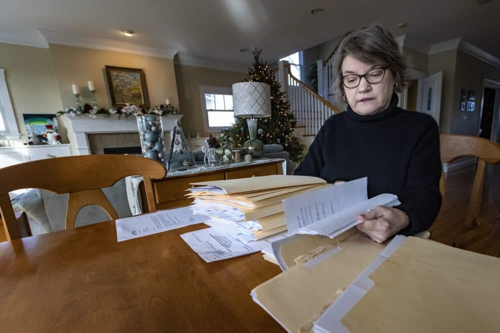 Susan Crowell files through the piles of paperwork she has accumulated throughout her workers’ compensation settlement case. She contracted COVID-19 while an employee at a Needham nursing home in the early days of the pandemic. (Jesse Costa/WBUR)