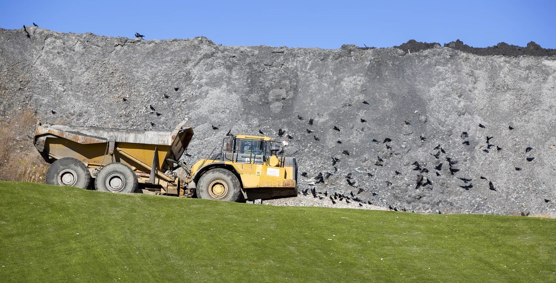 An earth mover drives along the ash mound beside Covanta's Haverhill waste facility that incinerates trash and generates electricity. (Robin Lubbock/WBUR)
