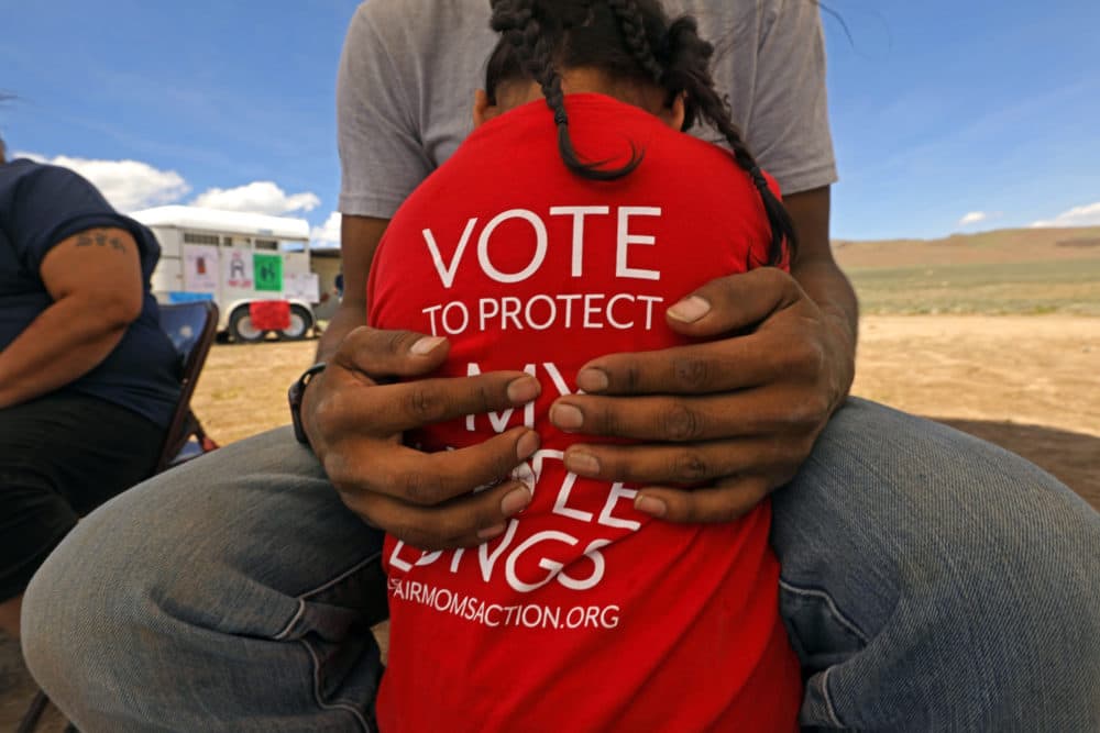 Redtail Hinkey, age 3, is held by his father during a protest by the Fort McDermitt Paiute Shoshone tribe against the proposed lithium mine in Thacker Pass, Northern Nevada, June 5, 2021. (Carolyn Cole/Los Angeles Times via Getty Images)