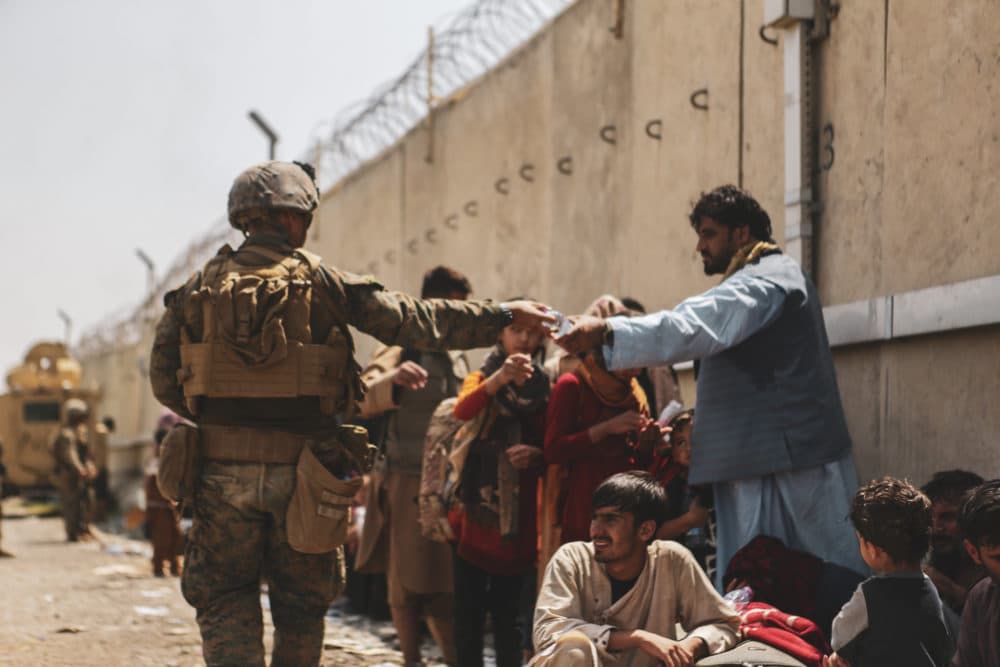 In this handout provided by the U.S. Marine Corps, a Marine with the 24th Marine Expeditionary unit (MEU) passes out water to evacuees during the evacuation at Hamid Karzai International Airport during the evacuation on August 21, 2021 in Kabul, Afghanistan. The U.S. military is assisting in the evacuation effort.  (Photo by Isaiah Campbell/U.S. Marine Corps via Getty Images)