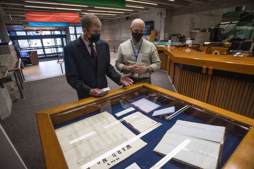 Secretary of State William Galvin, left, and Michael Comeau, executive director of the Massachusetts Archives, review documents dating back from the 19th century pertaining to the expansion of the right to vote in Massachusetts. (Jesse Costa/WBUR)