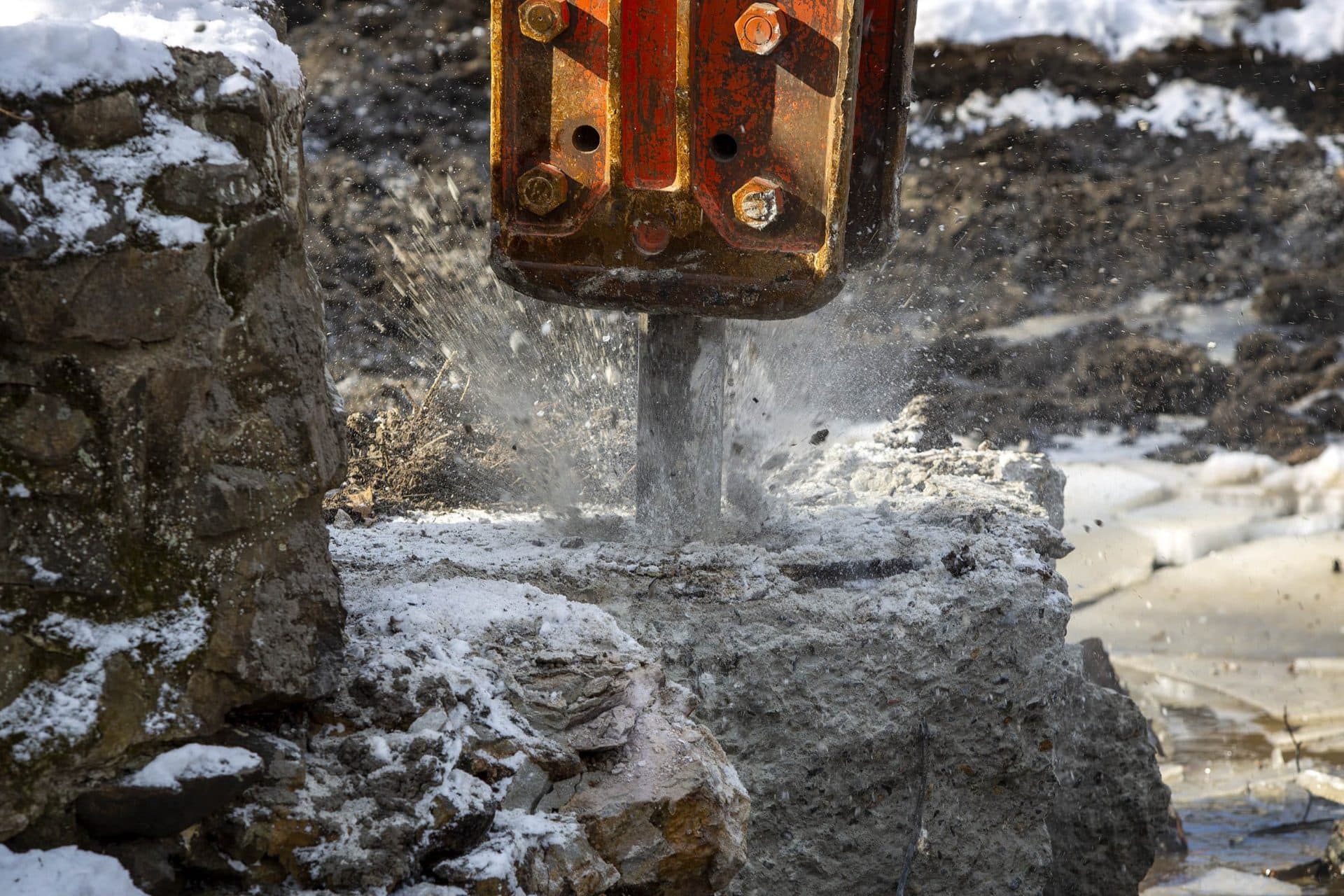 A jackhammer breaks up the spillway of the dam on Traphole Brook in Norwood. (Robin Lubbock/WBUR)