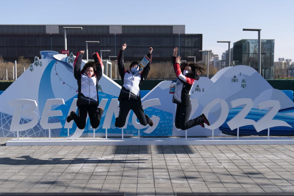 Olympic workers leap as they pose for photos with an installation near the Beijing Olympic Park at the 2022 Winter Olympics on Jan. 25, 2022, in Beijing. (Jae C. Hong/AP)