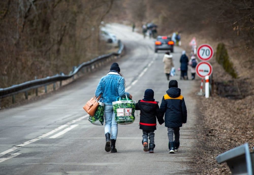 A woman with two children and carrying bags walk on a street to leave Ukraine after crossing the Slovak-Ukrainian border in Ubla, eastern Slovakia, close to the Ukrainian city of Welykyj Beresnyj, on February 25, 2022, following Russia's invasion of the Ukraine. (Peter Lazar/AFP via Getty Images)